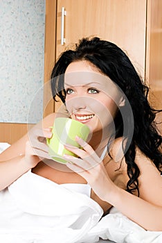 Beautiful woman drinking coffee in bed