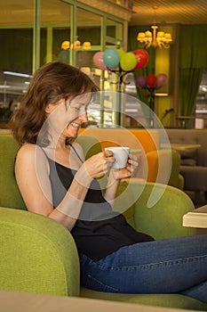 Beautiful woman drinking coffee in cafe. Daily life. Enjoy your life. Brunette girl with cup of tea on the sofa. Cozy lifestyle