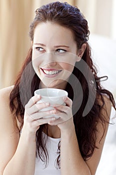 Beautiful woman drinking a cup of coffee in bed