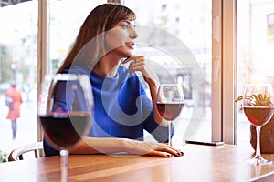 Beautiful woman drinking red wine with friends in cafe, portrait with wine glass near window. Vocation holidays bar concept