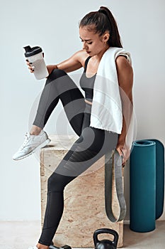 Beautiful woman drinking some water from plastic bottle after fitness