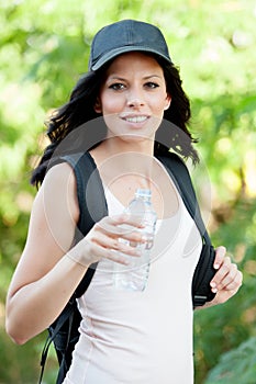 Beautiful woman drinking water while hiking