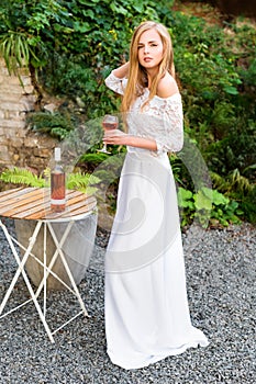 Beautiful woman drinking wine in outdoors cafe. Portrait of young blonde beauty in the vineyards having fun, enjoying a