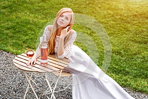 Beautiful woman drinking wine in outdoors cafe. Portrait of young blonde beauty in the vineyards having fun, enjoying a