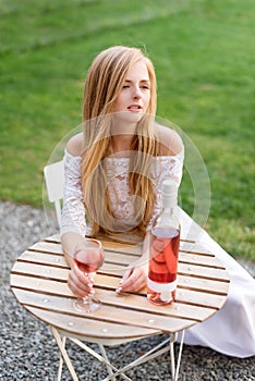 Beautiful woman drinking wine in outdoors cafe. Portrait of young blonde beauty in the vineyards having fun, enjoying a