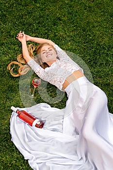 Beautiful woman drinking wine outdoors. Portrait of young blonde beauty in the vineyards having fun, enjoying a glass of