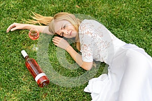 Beautiful woman drinking wine outdoors. Portrait of young blonde beauty in the vineyards having fun, enjoying a glass of