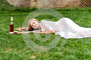 Beautiful woman drinking wine outdoors. Portrait of young blonde beauty in the vineyards having fun, enjoying a glass of