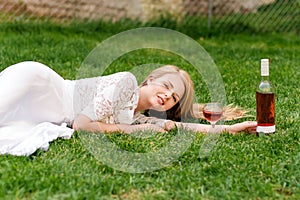 Beautiful woman drinking wine outdoors. Portrait of young blonde beauty in the vineyards having fun, enjoying a glass of