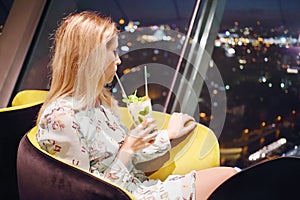 Beautiful woman drinks cocktail in restaurant,