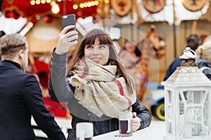 Beautiful woman drinks mulled wine and makes a selfy on mobile p