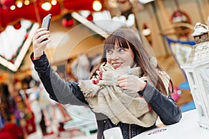 Beautiful woman drinks mulled wine and makes a selfy on mobile p