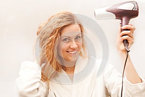 Beautiful woman drying her hair with hairdryer