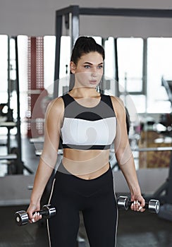 Beautiful woman with dumbbells training in gym