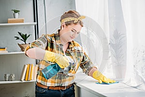 beautiful woman dusting windowsill