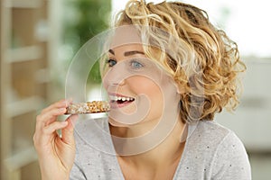 Beautiful woman eating cereal bar