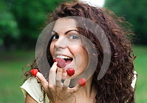 Beautiful woman eating fresh raspberry