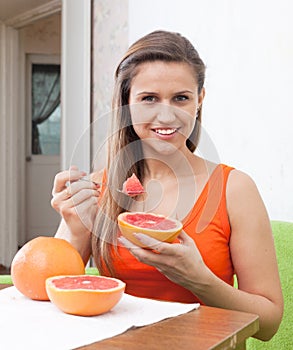 Beautiful woman eating grapefruit with spoon