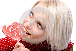 Beautiful woman eating a heart-shaped lollipop