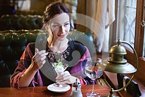 Beautiful woman eating ice cream in a cafe.