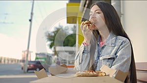 Beautiful woman eating pizza on street. Media. Woman snacking on pizza for lunch outside cafe. Young woman eats pizza on