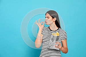 Beautiful woman eating potato chips on light blue background. Space for text