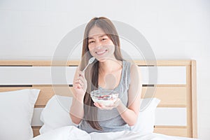 Beautiful woman eating yogurt with berries for breakfast