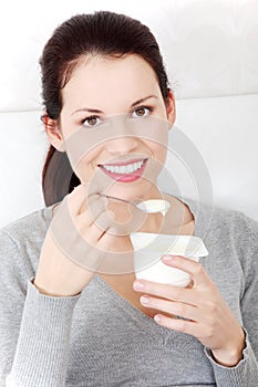 Beautiful woman eating a yogurt at home.