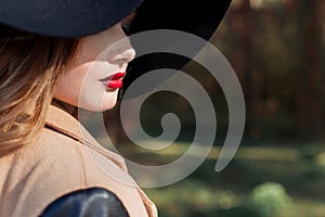 Beautiful woman in elegant black hat with large fields and bright red lipstick on her lips