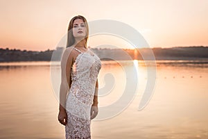 Beautiful woman in elegant dress on the beach at sunset