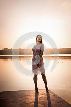 Beautiful woman in elegant dress on the beach at sunset