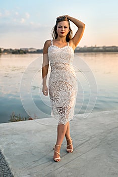 Beautiful woman in elegant dress on the beach at sunset