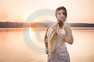 Beautiful woman in elegant dress on the beach at sunset