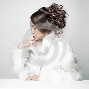 Beautiful woman with elegant hairstyle in white fur coat