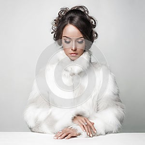 Beautiful woman with elegant hairstyle in white fur coat