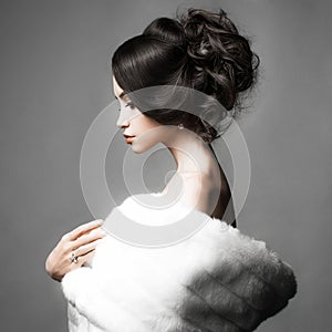 Beautiful woman with elegant hairstyle in white fur coat