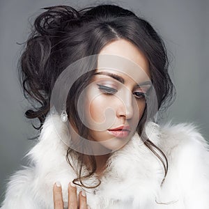 Beautiful woman with elegant hairstyle in white fur coat