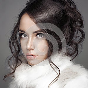 Beautiful woman with elegant hairstyle in white fur coat