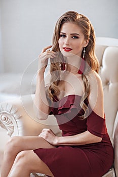 Beautiful woman in an elegant outdoor dress posing alone, sitting in a chair
