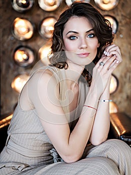 Beautiful woman in an elegant outdoor dress posing alone, sitting in a chair