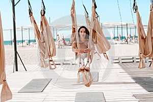 A Beautiful woman engaged in antigravity yoga outdoors by the sea on the beach