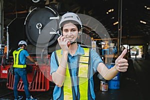 Beautiful woman engineer in factory talking on the radio wearing white helmet and work clothes