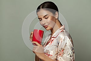 Beautiful woman enjoying the aroma of coffee and smiling