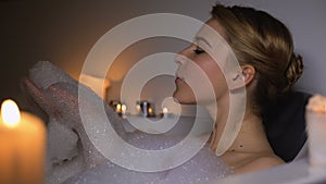 Beautiful woman enjoying bath relaxation, blowing bubbles, leisure time, closeup