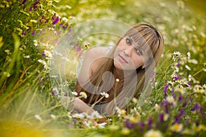 Beautiful woman enjoying daisy field, nice female lying down in meadow of flowers, pretty girl relaxing outdoor, having fun, holdi