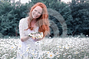 Beautiful woman enjoying daisy field, nice female in the meadow of flowers, pretty girl relaxing outdoor, having fun,holding plant