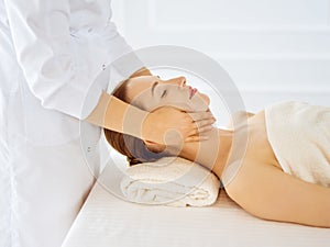 Beautiful woman enjoying facial massage with closed eyes in spa center. Relaxing treatment concept in medicine