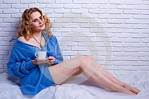 Beautiful woman enjoying morning coffee sitting in the bed. Cozi