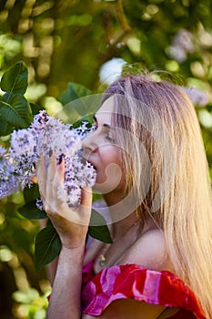 Beautiful Woman Enjoying the Smell of Lilac. Cute Model and Flowers.