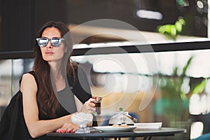 Beautiful woman enjoys cup of Turkish tea alone in cozy cafe, stunning fashion model with long dark hair